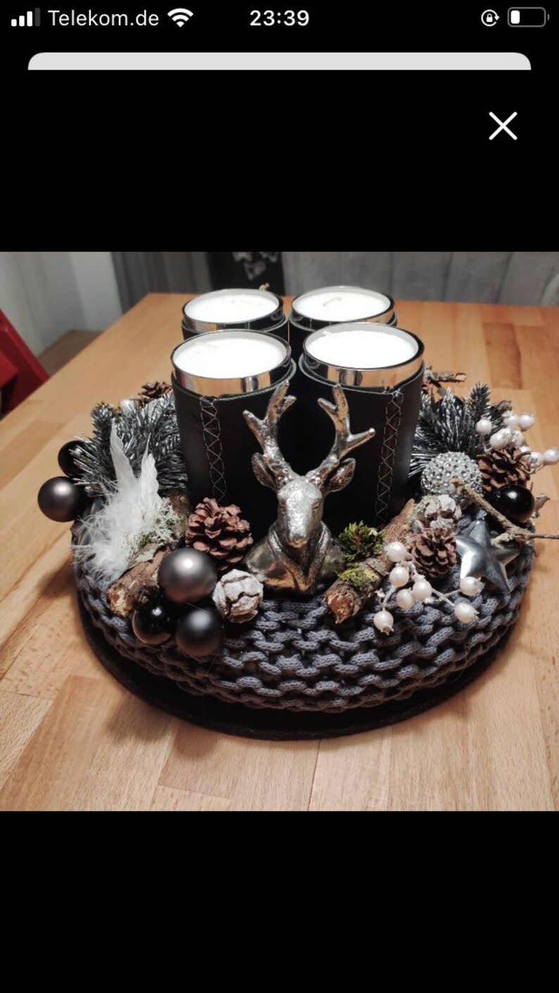 May include: A black and silver Christmas centerpiece with four candles, a deer figurine, pine cones, and white berries.