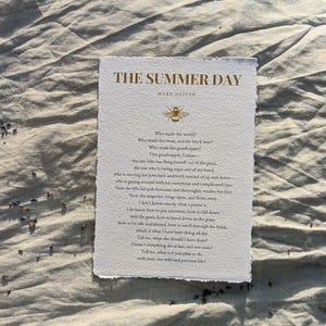 Puede incluir: Una impresión en papel texturizado con el título "THE SUMMER DAY" y el nombre del autor, Mary Oliver, en tipografía elegante. La impresión presenta un poema con una ilustración de abeja. El papel tiene un borde irregular.