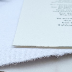 Może przedstawiać: Zbliżenie na białą kartkę papieru z nadrukowanym tekstem. Papier leży na białej, fakturowanej powierzchni.