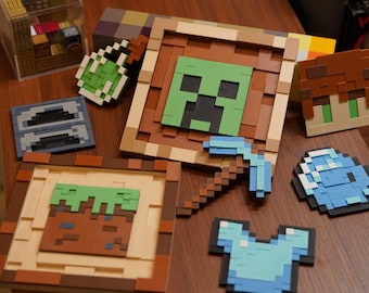 May include: A collection of pixelated Minecraft-themed items, including framed images of a Creeper face and a dirt block, a pickaxe, armor, and other game elements. The items are arranged on a wooden surface.