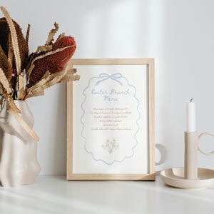 May include: A light blue and white printable Easter brunch menu with a decorative border and a small floral illustration. The menu lists "Breakfast and cold cheese goods, Turkey and spinach breakfast casserole, Roasted potatoes in garlic butter, Honey butter biscuits, Roasted fruit, Served cold with cream cheese frosting".