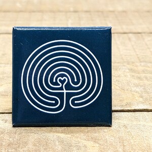 May include: A square, dark blue ceramic tile with a white labyrinth design. The labyrinth has a heart shape at the center.