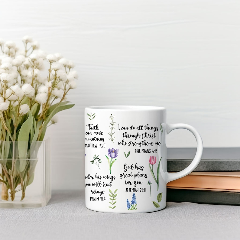 May include: White ceramic mug with a floral design and inspirational quotes. The quotes include "Faith can move mountains", "I can do all things through Christ who strengthens me", "God has great plans for you", and "Under his wings you will find refuge".
