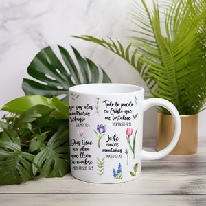 May include: White ceramic mug with inspirational quotes in Spanish and English. The quotes are surrounded by floral illustrations. The mug has a handle on the right side.