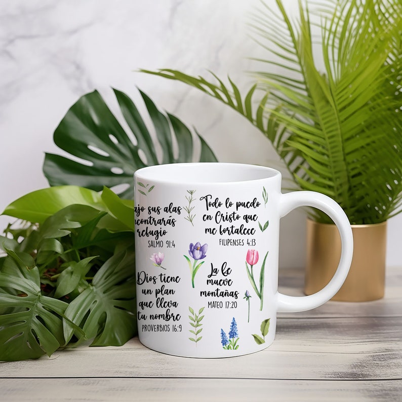 May include: White ceramic mug with inspirational quotes in Spanish and English. The quotes are surrounded by floral illustrations. The mug has a handle on the right side.