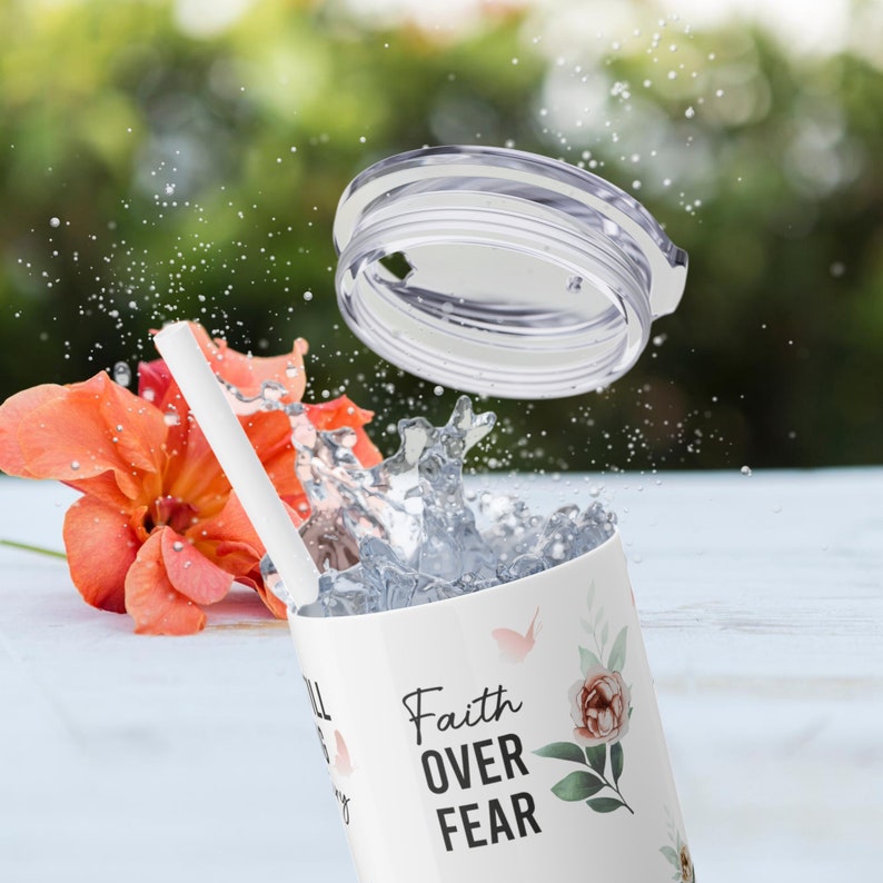 May include: White tumbler with a floral design and the text "Faith Over Fear". The tumbler has a clear lid and a white straw.