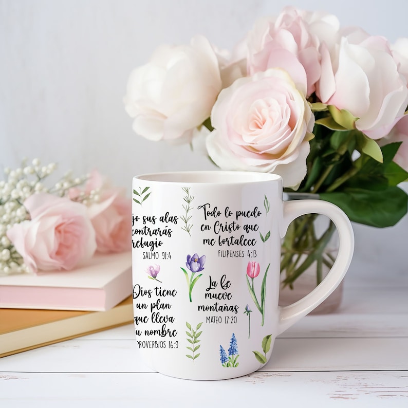 May include: White ceramic mug with a floral design and inspirational quotes in Spanish. The quotes include "Todo lo puedo en Cristo que me fortalece" (Philippians 4:13), "La fe mueve monta&ntilde;as" (Matthew 17:20), "Dios tiene un plan que lleva tu nombre" (Proverbs 16:9), and "Jo sus alas contrar&aacute;s refugio" (Psalm 91:4).