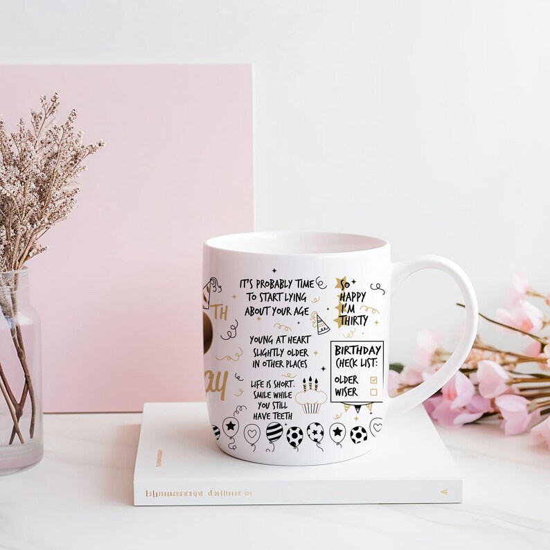 May include: White ceramic mug with a black and gold design. The mug has a handle and features text that reads "It's probably time to start lying about your age. So happy I'm thirty. Young at heart, slightly older in other places. Birthday check list: older, wiser".