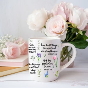 May include: White ceramic mug with a floral design and inspirational quotes. The quotes include "Faith can move mountains", "I can do all things through Christ who strengthens me", and "God has great plans for you".
