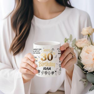 May include: White ceramic mug with a gold design. The mug features the text "Happy 30th Birthday Adam" with a party hat, balloons, and other celebratory graphics.
