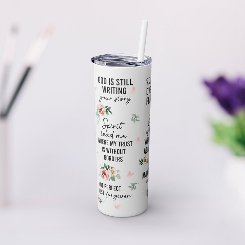 May include: White tumbler with a floral design and the text "God is still writing your story. Spirit lead me where my trust is without borders. Not perfect just forgiven."