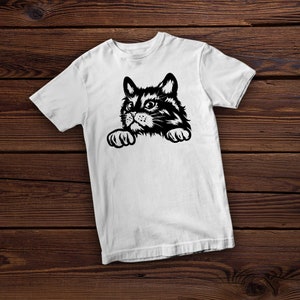 May include: White t-shirt with a black and white illustration of a cat peeking over the edge of the shirt.