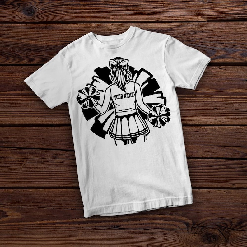 May include: White t-shirt with a black and white graphic of a cheerleader holding pom-poms. The graphic includes the text "YOUR NAME".