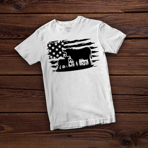 May include: White t-shirt with a black silhouette of a cow and calf standing in front of a distressed American flag.