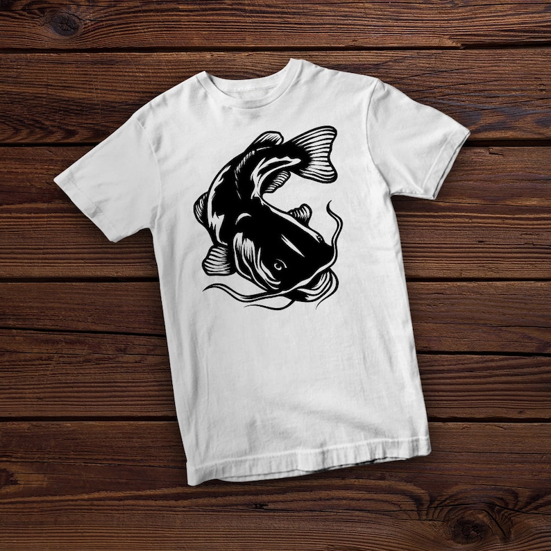 May include: White t-shirt with a black silhouette of a catfish. The catfish is facing the left side of the image and has its mouth open.