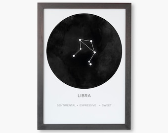 Puede incluir: Una impresión artística enmarcada con la constelación de Libra. La obra muestra un contorno blanco de la constelación sobre un círculo negro de estilo acuarela. La palabra "LIBRA" está centrada debajo, con las palabras "SENTIMENTAL • EXPRESIVO • DULCE" debajo.