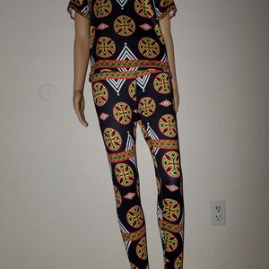 May include: A black and white patterned two-piece outfit with a short-sleeved top and leggings. The pattern features geometric shapes in red, yellow, and green.