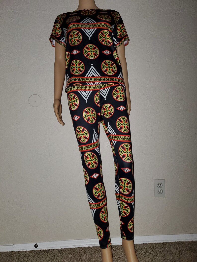 May include: A black and white patterned two-piece outfit with a short-sleeved top and leggings. The pattern features geometric shapes in red, yellow, and green.