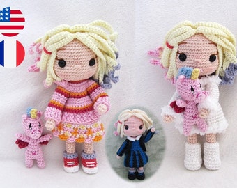 May include: Two crocheted dolls with blonde hair and pink and white clothing. The doll on the left is holding a pink crocheted unicorn. The doll on the right is wearing a white dress and holding a pink crocheted unicorn.