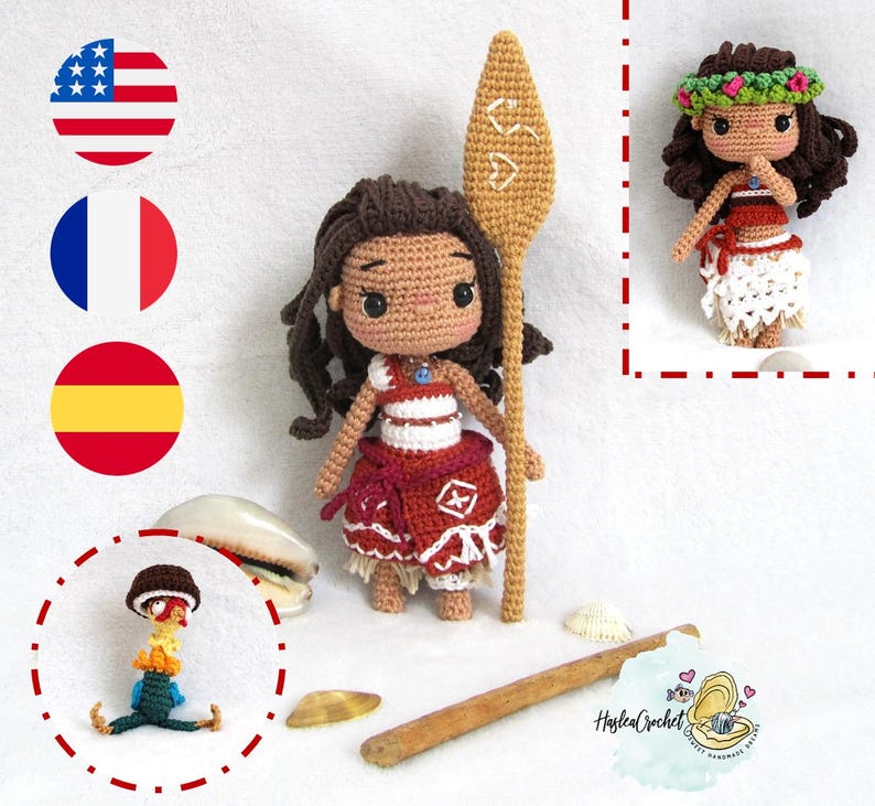 May include: A crocheted doll of Moana from the Disney film Moana, holding a wooden paddle. The doll is wearing a red and white dress and a blue necklace. The doll is standing on a white surface with seashells scattered around it.