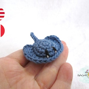May include: A small, blue crocheted stingray with black eyes. The stingray is about the size of a person's palm.