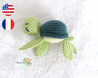 May include: A crocheted green and teal turtle with a white shell. The turtle has a cute face with black eyes and a small mouth.