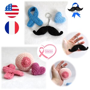 Peut inclure: Plusieurs articles crochetés à la main, dont un porte-clés avec une moustache noire, un ruban bleu et un sein rose avec un mamelon. Également, un cœur rose et un ruban rose. L'image comprend un logo du Mois de sensibilisation au cancer du sein.
