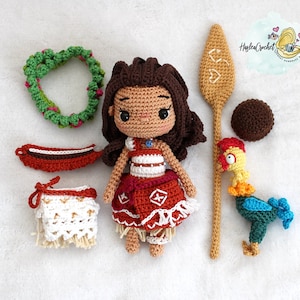 May include: Crocheted amigurumi doll of Moana from Disney's Moana, wearing a red and white dress, a lei, and a blue necklace. The doll is surrounded by other crocheted items, including a rooster, a paddle, and a flower lei.
