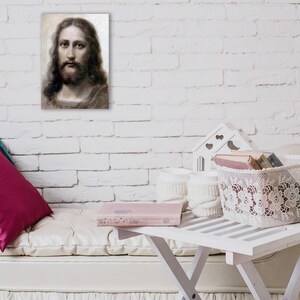 May include: A white couch with pink and purple pillows, a white table with a book and a white lace basket filled with books. The wall behind the couch is white brick.