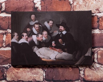 May include: A painting depicting a group of men gathered around a table, observing a dissected body. The men are dressed in 17th-century attire, and the scene is lit by a single light source. The painting is a classic example of Dutch Golden Age art.