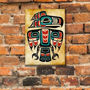 Puede incluir: Una impresión rectangular sobre lienzo con un diseño nativo americano estilizado. La obra de arte presenta una figura simétrica de pájaro o espíritu en negro, rojo y turquesa sobre un fondo beige. La impresión está montada en una pared de ladrillo.