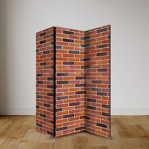 Könnte beinhalten: Ein dreiteiliger Raumteiler mit einem Backsteinmauer-Design. Der Raumteiler hat einen schwarzen Rahmen und besteht aus Paneelen mit einem sich wiederholenden Muster aus roten, braunen und orangefarbenen Ziegeln. Er steht auf einem Holzboden.