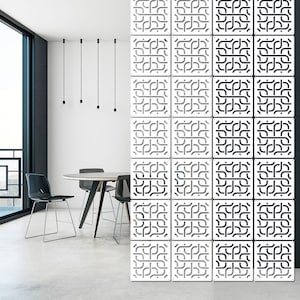 Könnte beinhalten: Ein modernes Interieur mit einem weißen und schwarzen geometrischen Raumteiler. Der Teiler besteht aus quadratischen Paneelen mit einem komplizierten, sich wiederholenden Muster. Ein runder Tisch und Stühle sind im Hintergrund zu sehen, sowie Hängeleuchten.
