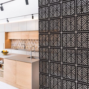 May include: Black room divider made of wood with a geometric pattern. The divider is made up of multiple panels that can be arranged in different ways. The divider is shown in a modern kitchen setting.
