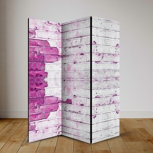 Könnte beinhalten: Ein dreiteiliger Raumteiler mit einem Ziegelmauer-Design. Die Paneele sind weiß gestrichen mit rosa Akzenten, was einen abgenutzten Look erzeugt.