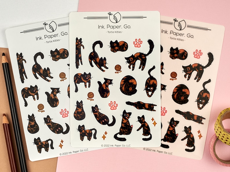 Op de afbeelding: Drie vellen met stickers met illustraties van schildpadkatten in verschillende poses. De stickers zijn gedrukt op transparant, glanzend papier en hebben een witte achtergrond. De tekst "Ink. Paper. Go. - Tortie Kitties -" is bovenaan elk vel gedrukt.
