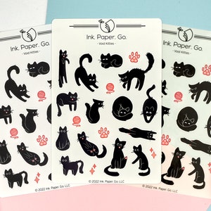 May include: Three sheets of stickers featuring black cats in various poses. The stickers are on a white background with pink accents. The text "Ink. Paper. Go. - Void Kitties -" is printed on each sheet.