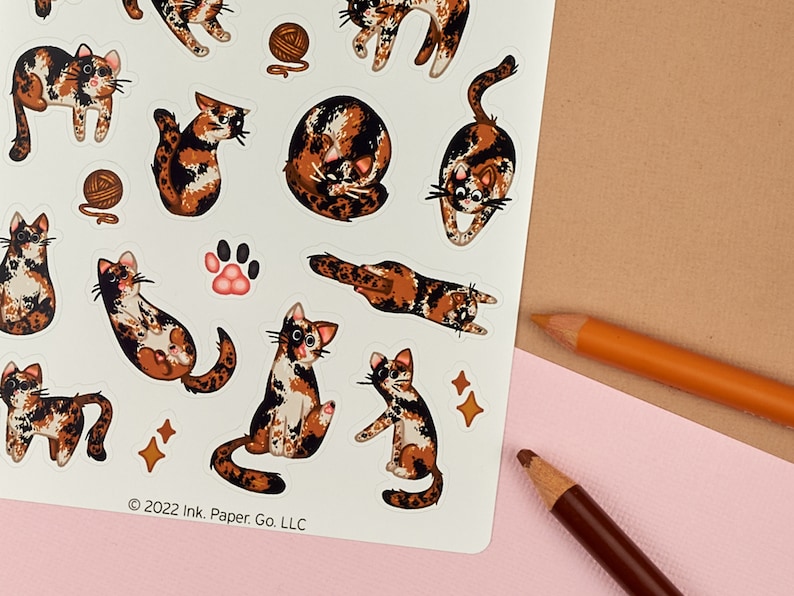 Puede incluir: Una hoja de pegatinas con una variedad de adorables gatos calic&oacute; en diferentes poses. Las pegatinas est&aacute;n sobre un fondo blanco con un aviso de copyright en la parte inferior que dice "2022 Ink. Paper. Go. LLC."