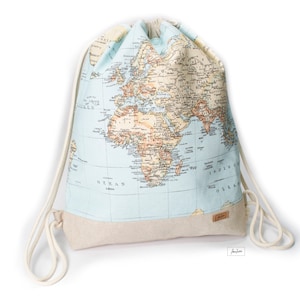 May include: Drawstring backpack with a world map design in blue, tan, and brown. The bag has a light blue upper section with a detailed map print and a tan base. White drawstring cords complete the design.