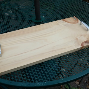 May include: A wooden serving tray with two silver handles. The tray has a natural wood finish and a blue resin inlay.