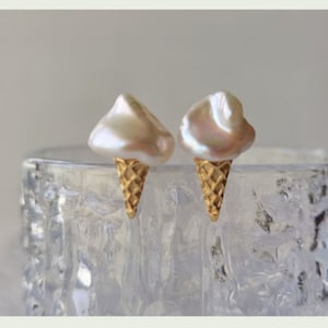Puede incluir: Un par de pendientes de cono de helado de oro con tapas de perlas blancas.