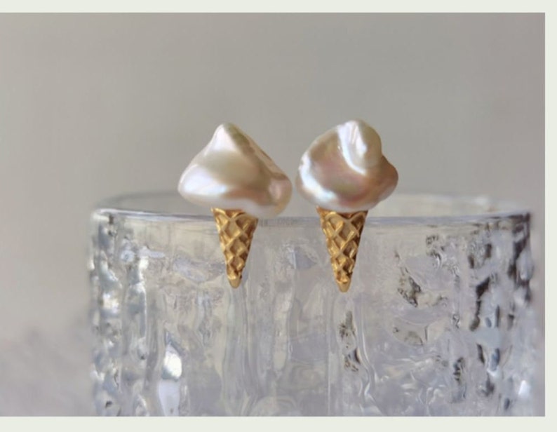 Puede incluir: Un par de pendientes de cono de helado de oro con tapas de perlas blancas.