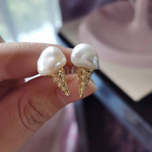 Puede incluir: Un par de pendientes de oro en forma de cono de helado con perlas blancas.