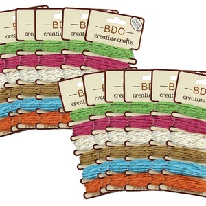 Può includere: Confezioni di spago colorato in varie tonalità, tra cui verde, rosa, bianco, marrone, blu e arancione. Ogni confezione è etichettata con "-BDC- creative crafts" e "PAPER DECOR". Lo spago è probabilmente per lavori artigianali o decorativi.
