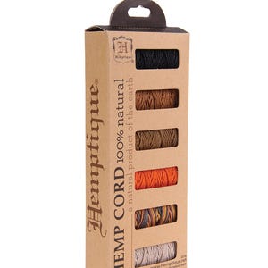 May include: A vertical cardboard box containing six mini spools of Hempique 100% natural hemp cord in black, brown, tan, orange, multicolored, and off-white. The packaging displays the text Hempique, HEMP CORD 100% natural, and 9.8 yards each.