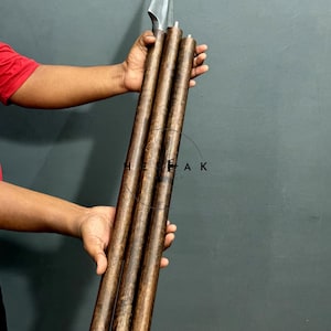 Può includere: Un bastone in legno in tre pezzi dotato di una punta di lancia in metallo sulla parte superiore. Il bastone è realizzato in legno marrone scuro testurizzato di forma cilindrica. Il testo HEBEAK è stampato in lettere nere al centro.