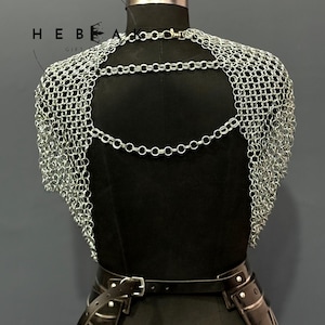 May include: A silver chainmail shoulder piece with a backless design. The chainmail is draped over a black mannequin, with a black leather belt and accents visible below. The image includes the text "HEBE GIFTS".