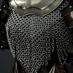 May include: Close-up of medieval armor, featuring a silver chainmail shirt and a polished steel breastplate. The armor has dark leather accents and is designed to protect the torso. The image shows the intricate details of the metalwork.