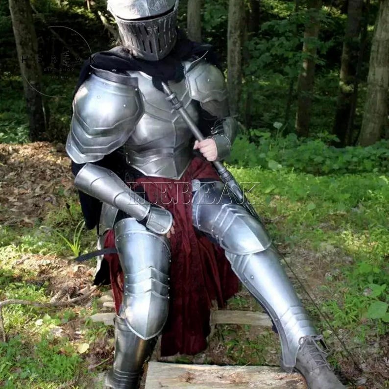 May include: A full suit of silver armor with a helmet, worn by a person sitting on a wooden platform in a forest setting.