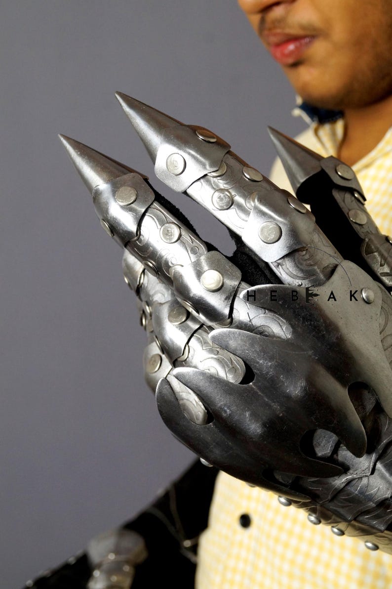 K&ouml;nnte beinhalten: Ein silberner Metall-Klauenhandschuh mit spitzen Fingern und Nieten. Der Handschuh wird von einer Person mit einem gelben Hemd getragen. Der Text "HEBEAK" ist auf dem Handschuh sichtbar.